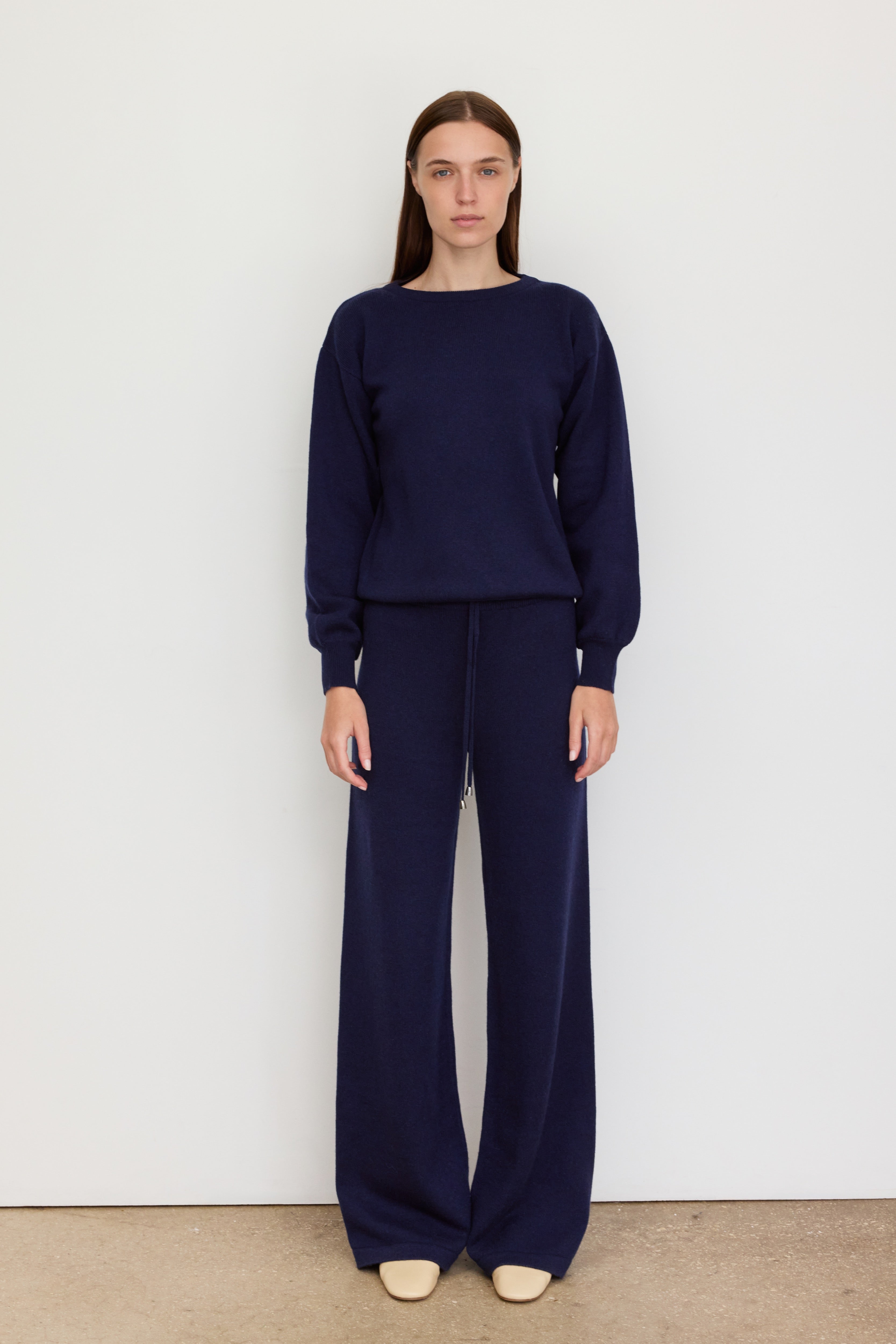 Model wearing the Verona navy oversized sweater with high neck and relaxed fit, paired with white shorts in a sunny studio setting.